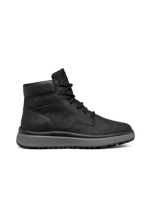 Bottines en cuir noir avec un col rembourré, bout rond et semelle en caoutchouc grise, comportant six œillets et un système de laçage.