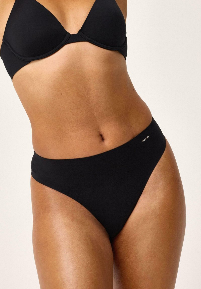 Zwarte naadloze bikinionderkant met een hoge taille, rekbare stof en minimale branding op de tailleband. Gladde textuur, geen patronen.