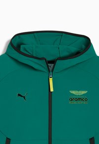 Giacca verde con cappuccio e zip, con dettagli neri. Presenta una cerniera gialla, logo Puma nero e marchio Aston Martin sul petto.