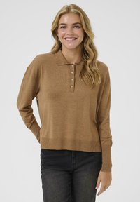 Brun stickad polo-tröja med spetsig krage, som har fem knappar vid halsen, långa ärmar och en avslappnad passform.