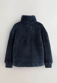 Pullover in fleece, blu navy, colletto alto, dalla texture particolare, design oversize con polsini a costine. Vista posteriore che mostra dettaglio delle cuciture e delle toppe.