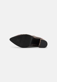 Chaussure à bout pointu avec un dessus texturé brun et noir. Caractéristiques d'une semelle en caoutchouc noir avec un motif strié pour une meilleure adhérence.