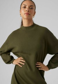 Maglione lavorato a maglia verde oliva con collo alto, vestibilità ampia e maniche lunghe. Il tessuto testurizzato conferisce un aspetto morbido con dettagli minimal.
