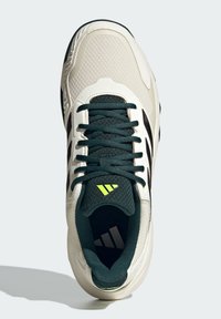 Baskets de sport blanches et vertes avec une tige en maille, des superpositions texturées, des rayures noires et des accents jaunes fluo. Présente des lacets texturés et une semelle intérieure.