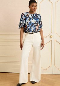 Lillelille lillede lillestamine lilledega, sinised, mustad ja oranžid toonid; koos valgete laiade pükste ja musta vööga.