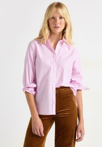 Lyserød skjorte med knapper og fine blå og hvide striber, optrukne ærmer og lige snit. Sammen med brune kordfløjl bukser.