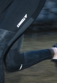 Svarta träningsleggings med ett strukturerat mönster, med "Terrex"-logotypen och en åtsittande design, lämpliga för rörelse och prestation.