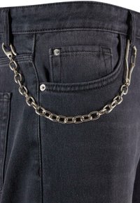 Zwarte denim jeans met een zilveren ketting bevestigd aan de achterzak, met een gestructureerde stof en eenvoudige hardwareaccenten.
