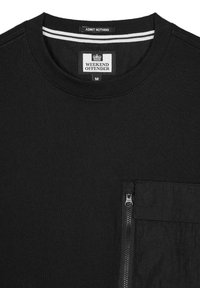 Sort t-shirt lavet af bomuld med rund hals, med en struktureret lynlås-lomme på venstre bryst og hvid stripe-detalje ved halsen.