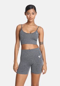 Sada šedého športového podprsenka a vysokých šortiek vyrobená z textúrovanej látky, obsahujúca nastaviteľné ramienka a detail s logom na boku.