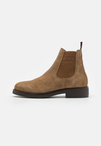 Brown suede Chelsea boot featuring elastic side panels, a pull tab, and a low-contrast rubber sole for a streamlined design.