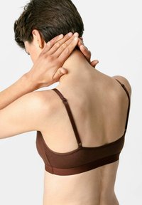 Bruine draadloze bh met verstelbare bandjes, een gladde textuur en een naadloos ontwerp. Heeft een brede band voor ondersteuning en comfort.