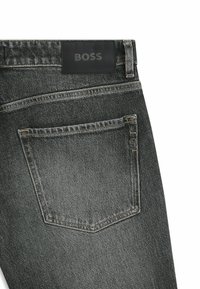 Ciemnoszare jeansy z denimu posiadają czarną skórzaną metkę na pasku z tłoczonym napisem "BOSS". Z tyłu znajduje się kieszeń z subtelnym przeszyciem i detalem z logo.