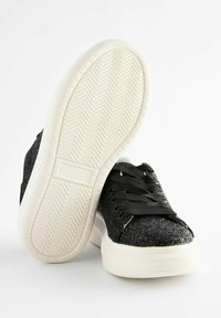 Schwarze Glitzer-Sneaker mit einer strukturierten Oberseite, flachen schwarzen Schnürsenkeln und einer weißen Gummisohle mit Fischgrätenmuster.