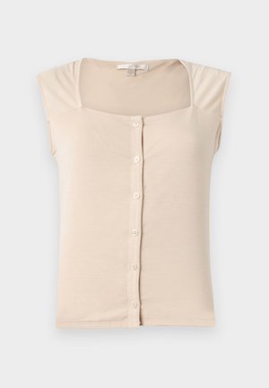 Bēša bezroku blūze ar kvadrātveida kakla izgriezumu un pogu aizdari priekšpusē, izgatavota no maiga, viegla auduma.