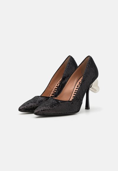 Escarpins noirs en tissu texturé, à bout pointu et talon fin de 10 cm avec un accent blanc à l'arrière. L'intérieur est doublé de beige.