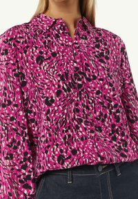 Camicia da uomo rosa con un motivo testurizzato di forme astratte in bianco e nero. Presenta un colletto a punta e maniche lunghe.
