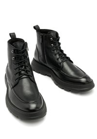 Czarne skórzane botki sięgające kostki mają okrągły nos, sznurowaną konstrukcję i zamek błyskawiczny z boku. Gruba, teksturowana podeszwa zapewnia dodatkową przyczepność i stabilność.
