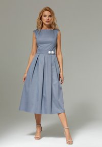 Jasnoniebieska sukienka do kolan z dopasowanym gorsetem, plisowaną spódnicą i dwoma białymi guzikami w talii. Gładka tekstura i rękawy typu cap.