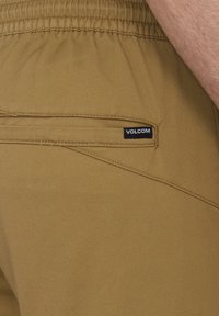 Szorty w kolorze khaki wykonane z wytrzymałego materiału, z płaską tylną kieszenią z czarną metką "Volcom" oraz elastycznym pasem dla wygody.