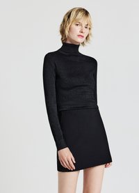 Schwarzes Langarm-Turtleneck-Oberteil mit körperbetonter Silhouette und subtiler shimmer, kombiniert mit einem kurzen schwarzen Rock. Glatte Textur, minimalistisches Design.