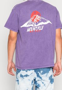 Lila bomulls t-shirt med en grafisk bild av Mount Fuji och en röd sol på baksidan, med en avslappnad passform och korta ärmar.