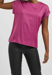 Top di seta fucsia con maniche corte, scollatura rotonda e vestibilità rilassata, abbinato a pantaloni in pelle nera. Texture liscia e lucida.