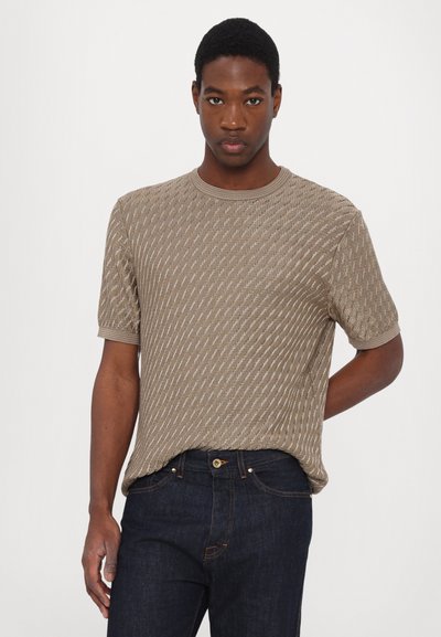 C�ămașă cu mâneci scurte, din tricot texturat, de culoare bej, cu un design cu un model. Are un decolteu rotund și manșete ribbrate, asortată cu blugi închisi la culoare.