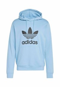 Felpa leggera blu realizzata in un tessuto morbido, caratterizzata da un logo trefoil nero di Adidas e tre strisce nere sul petto. Cappuccio regolabile con cordoncino.