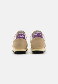 VEJA-sneakers med en beige gammetoverdel, lilla detaljer på hælen og en teksturert gummisåle. Designet har en lav topp silhuett.