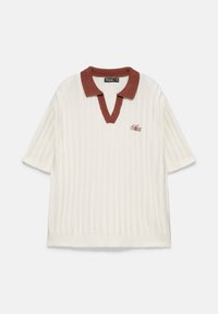 Chemise en tricot crème à manches courtes avec côtes verticales, col marron et petit texte brodé sur la poitrine gauche.