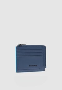 Cartera azul marino hecha de cuero suave con cierre de cremallera, cinco ranuras para tarjetas, logo grabado y bordes en azul contrastante.