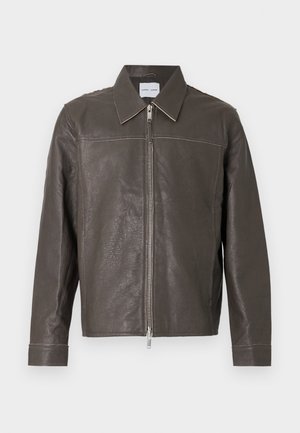 Bruine leren jas met een ritssluiting aan de voorkant, klassieke kraag en lange mouwen. Kenmerkt zich door contrasterende stiksels langs de naden. Gladde textuur.