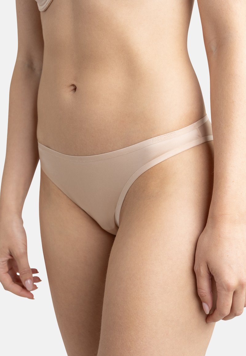 Bas de bikini beige sans coutures avec une taille basse. Fabriqué en tissu lisse et extensible avec un design minimaliste et sans hardware visible.