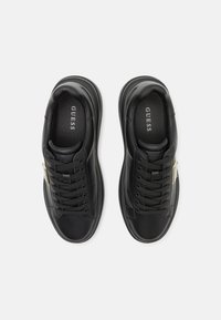 Zapatillas de cuero negras con punta redonda, superficie texturizada, cierre de cordones y un pequeño acento dorado en el lateral con el logo de la marca.