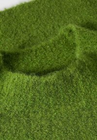 Pull en tricot vert avec une finition texturée et douce, doté d'un col rond. Le tissu semble confortable et chaud avec différentes nuances de vert.