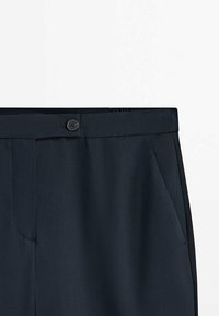 Dark navy trousers featuring a smooth texture, a single button closure, and side pockets. Subtle pattern visible in fabric.
