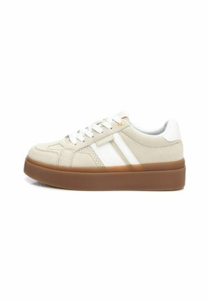 Zapatillas beige con rayas blancas, con un upper texturizado, puntera redonda y una suela de goma marrón gruesa. Cordonera en color a juego.