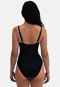 Maillot de bain une pièce noir avec des bretelles ajustables, une texture lisse et des ouvertures de jambe très échancrées, mettant en valeur une silhouette ajustée.