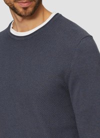 Marineblauer strukturierter Pullover mit Rundhalsausschnitt, darunter befindet sich ein weißer Kragen. Eine Nahaufnahme hebt die Material- und Strickmusterdetails hervor.