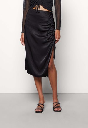 Black satin skirt with side ruching and a high slit. Features a smooth texture and a flowing design that drapes elegantly.