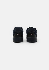 Sneaker blu navy con dettagli in pelle nera, colletto imbottito e mesh testurizzato. Presenta una branding minimale sul tallone e una suola in gomma solida.
