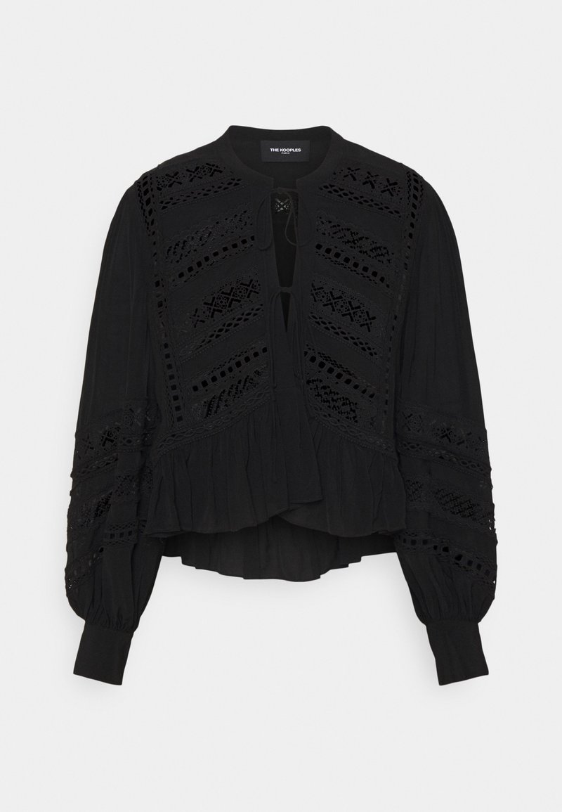 Svart långärmad blus med spetspaneler, puffärmar, knytfront och volangkant, uppvisad mot en enkel bakgrund.
