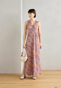 Robe maxi avec un motif zigzag coloré en rose, jaune et bleu. Tissu léger ; conçue avec un décolleté croisé et sans manches.
