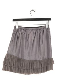 Růžový volánkový sukénka vyrobená z hladkého materiálu s elastickým pasem, zavěšená na černém klipovém držáku pro vystavení.