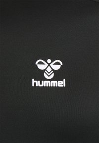Tissu noir à la texture lisse avec un logo Hummel blanc, qui comprend une abeille stylisée et le nom de la marque en lettres majuscules.