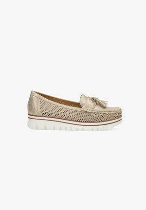 Mocasines de cuero perforado color beige con detalle de borlas, que cuentan con una suela de goma blanca con rayas decorativas y un diseño de punta redondeada.