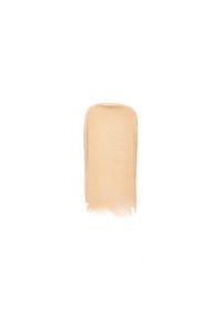 Swatch di fondotinta liquido in una tonalità beige caldo, consistenza liscia, forma ovale allungata con una sfumatura graduale ai bordi.