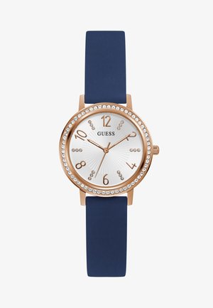 Rúžovo-zlaté hodinky s okrúhlym bielym textúrovaným ciferníkom, námorníckym silikónovým remienkom a kryštálovými akcentami okolo lunety. Majú výrazné číslice a ručičky.