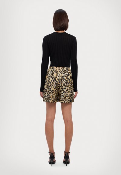 Top de manga larga negro con textura acanalada, combinado con pantalones cortos de leopardo dorado, con cintura elástica y tela suave. Sandalias de tacón negras.